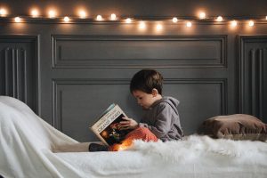 child reading below fairy lights